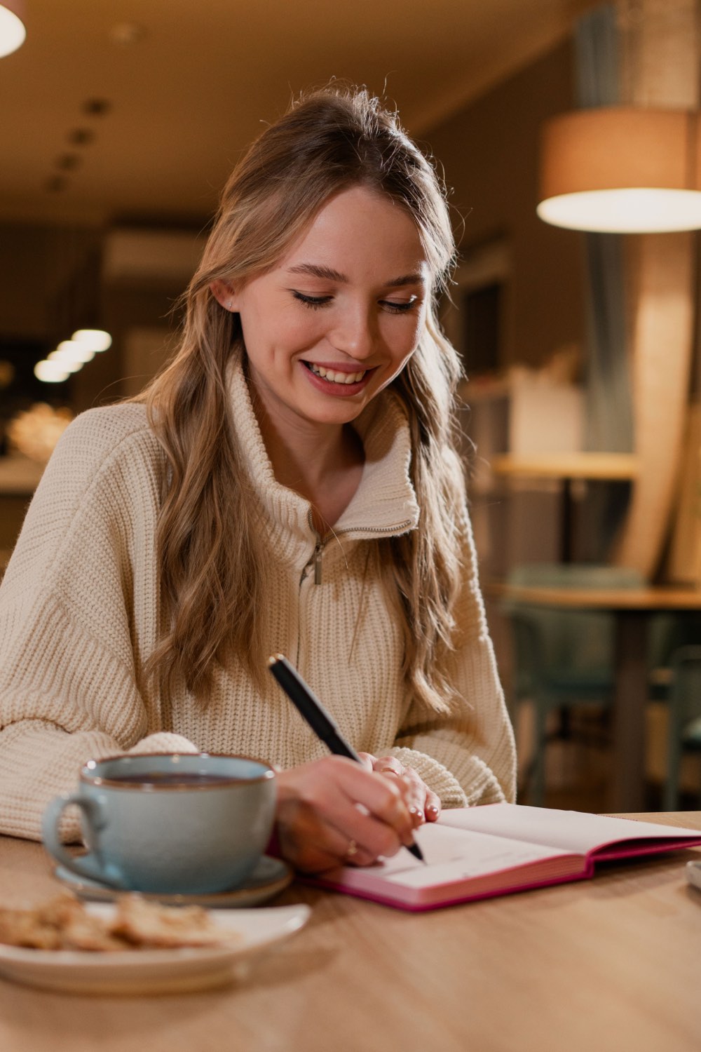 Persona planeando su semana con calma, cuaderno y café, en luz cálida